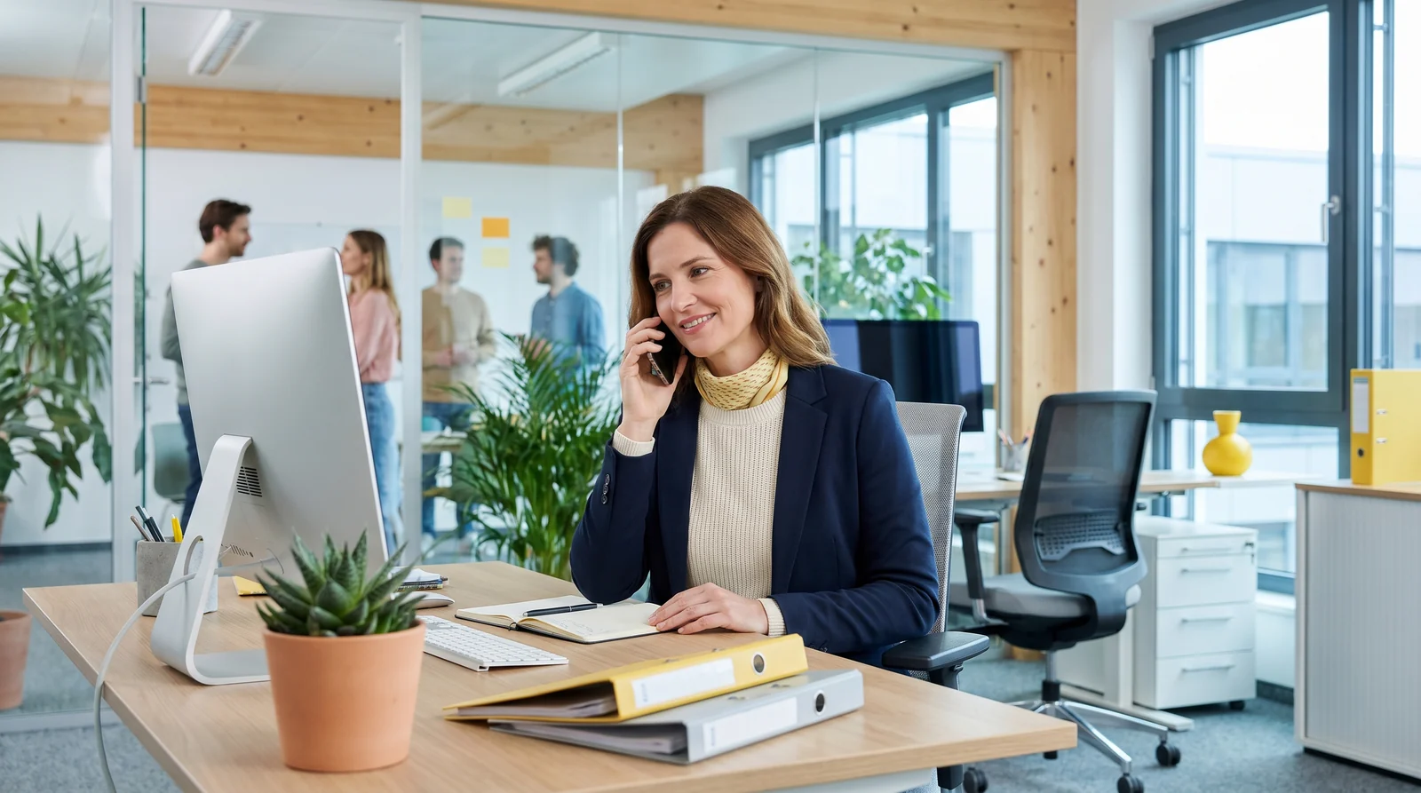 Mitarbeiter einer Hausverwaltung nimmt im hellen Büro eine Mieteranfrage am Telefon entgegen